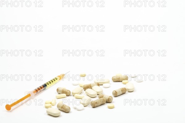 Syringe with vaccine next to a group of pills on white background and copy space