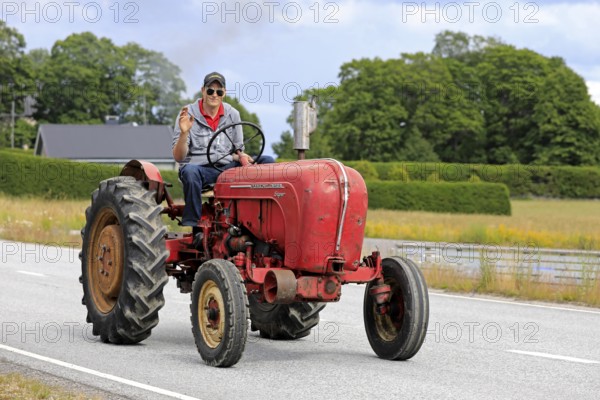 Kimito, Finland. July 6, 2019. Young man greets as he drives classic Porsche-Diesel Super Tractor on Kimito Tractorkavalkad, vintage tractor parade