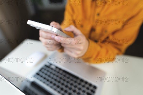 Female student's hands with a phone on the background of a modern laptop and desktop. Freenacer working from home, hipster profession