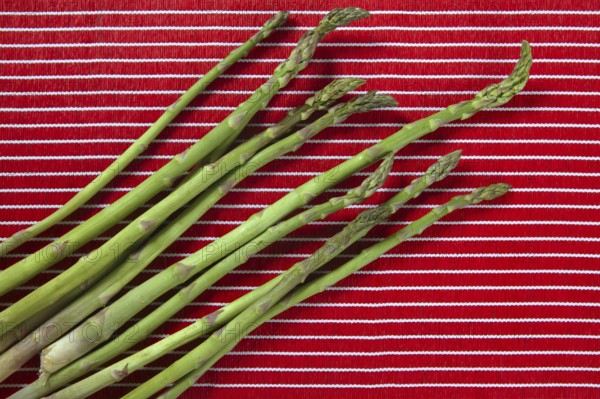 Green asparagus over red tablecloth background