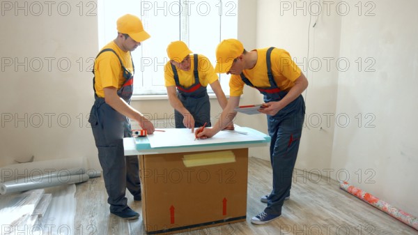 Preparatory phase of house renovation. Working group is studying a plan of apartment. Business professional contractor