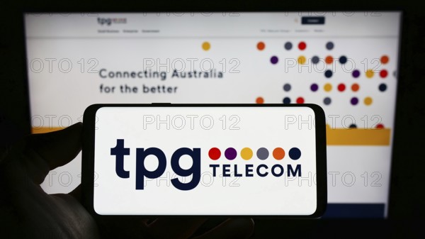 Stuttgart, Germany, 12-30-2022: Person holding cellphone with logo of Australian company TPG Telecom Limited on screen in front of business webpage. Focus on phone display, Europe