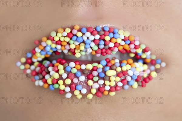 Close up of woman lips with multicolored sweet pearls
