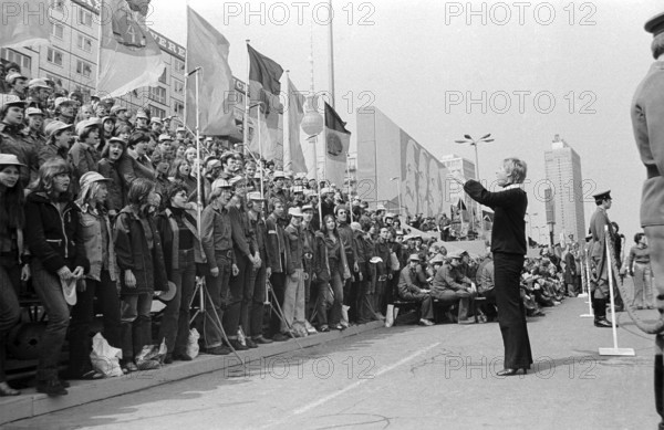 01.05.1980 GDR East Berlin Mitte district. Scene on the fringes of the First of May demonstration. A young woman conducts a choir of members of the Free German Youth during the demonstration in Karl-Marx-Allee. Berlin