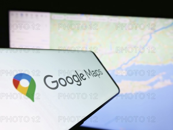 Stuttgart, Germany, 03-10-2023: Smartphone with logo of web mapping platform Google Maps on screen in front of website. Focus on center-right of phone display, Europe