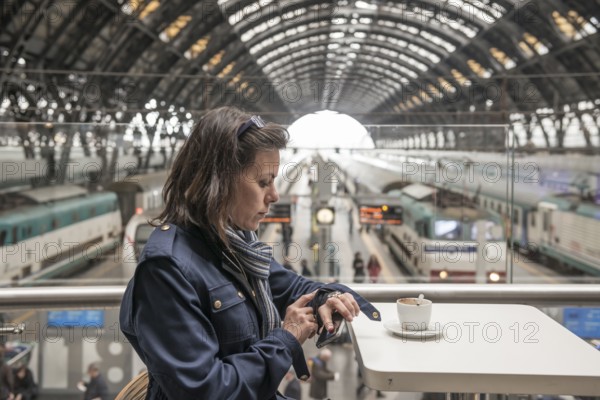 Woman in a Restaurant Drinking Coffee and Looking at Her Watch in Railroad Station in Milan, Lombardy, Italy, Europe