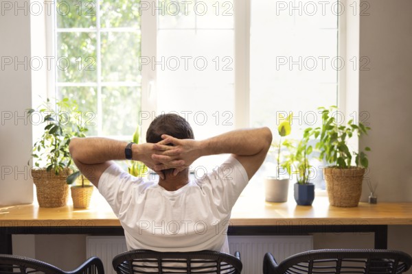 Young personal development coach answering the client by email by a laptop while having break in a coffee shop. Hipster guy searching the information typed in a mobile phone on a laptop