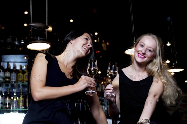 Two beautiful young women sharing their friendship and celebrating with champagne, in a fancy nightclub