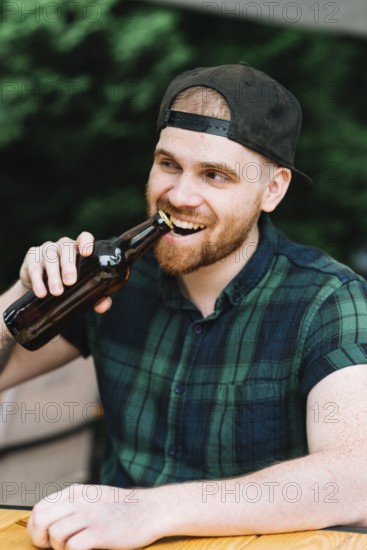Man opening beer bottle cap with his teeth