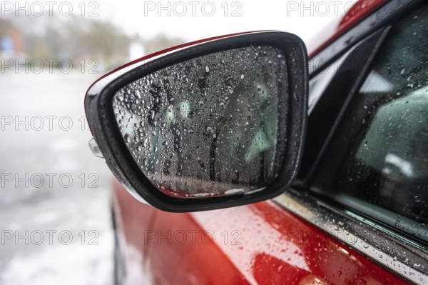 Fine water droplets on a side mirror of a red car