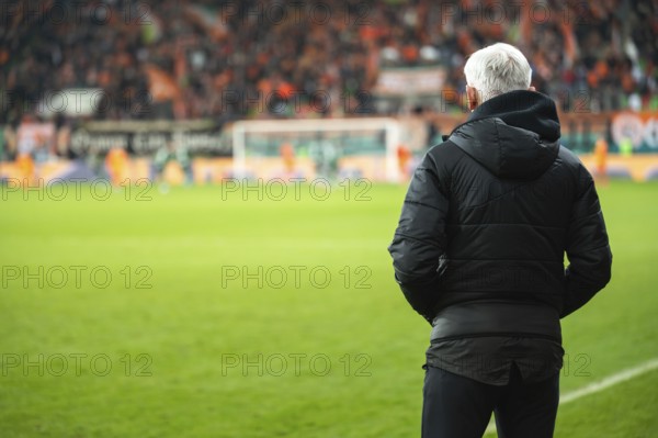 Head coach's back and soccer match at the stadium in the background