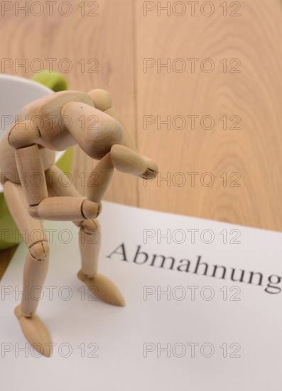 Letter of warning on a table, desperate figure sitting on a cup