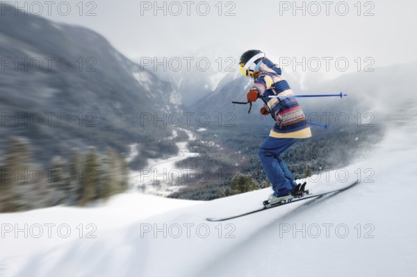A female athlete skier rides a freeride in a winter forest in the mountains. Jump against the backdrop of snow-covered trees and the setting sun