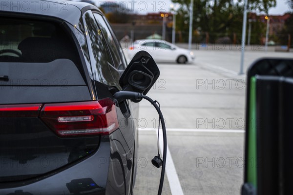 Black electric car charging at a parking lot