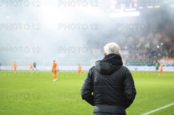 Head coach's back and soccer match at the stadium in the background