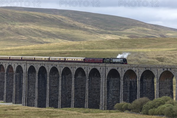 Steam train crossing Ribblehead Viaduct, railway bridge over the valley of the River Ribble at the foot of the mountain Whernside, North Yorkshire, England, Great Britain