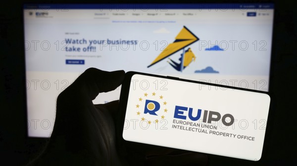 Stuttgart, Germany, 10-17-2023: Person holding cellphone with logo of European Union Intellectual Property Office (EUIPO) in front of webpage. Focus on phone display, Europe