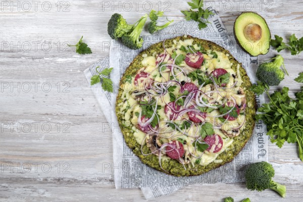 Food, Crust Broccoli base low carbs keto pizza with salami, avocado on vintage newspapper. Top view