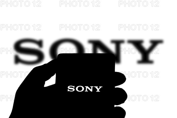SONY is Japanese corporation. SONY is video game console company and video game publisher. Smartphone with SONY logo on screen surrounded by gamepads.