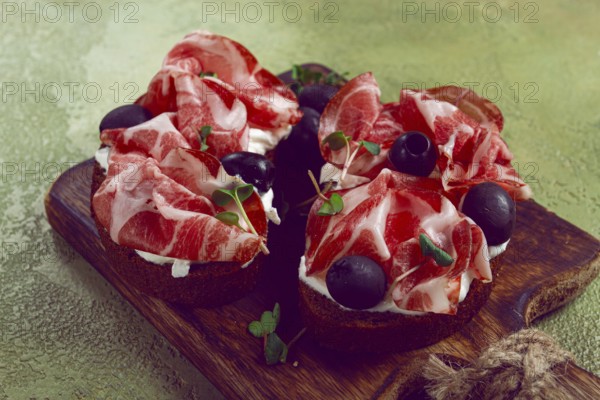 Sliced cured ham, sandwiches with prosciutto and black olives, Italian dish, delicacy, Parma ham, breakfast, top view, no people