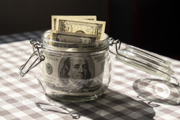 Dollar banknote saving money in glass jar. Consumption and economy Collecting money. Tips. Business, finance, saving, banking and people concept. Extra money, passive income. Saving for travel, crisis, house, car, education, retirement