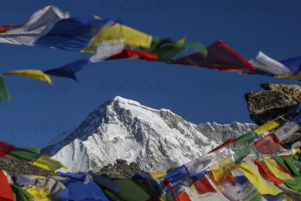 The eight-thousander Cho Oyu, the sixth-highest mountain on the planet, seen shortly after sunrise with some colourful Buddhist prayer flags in the foreground, marking the summit of Gokyo Ri, the popular trekking peak in the Everest Region. Photographed on a clear, late November day during the autumn, post-monsoon trekking season in the Nepali Himalayas. The Three Passes Trek in the Khumbu Region. Sagarmatha National Park, the UNESCO World Heritage Site. Solukhumbu, Nepal, Asia