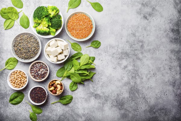 Top view of different vegan protein sources with space for text: beans, lentils, quinoa, tofu, vegetables, nuts, chickpeas, rice, stone background. Healthy balanced vegetarian nutrition for vegans