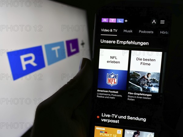 Stuttgart, Germany, 02-13-2024: Person holding cellphone with webpage of German entertainment platform RTL plus in front of business logo. Focus on center of phone display, Europe