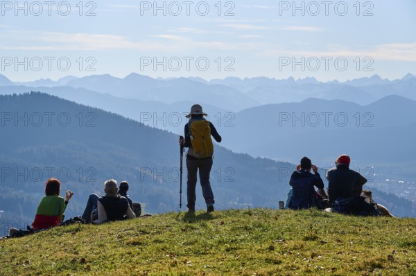Hikers rest on the summit of Sonntratn, also known as Schürfenkopf, and look into the Karwendel, near Bad Tölz, Bavarian Prealps, Upper Bavaria, Bavaria, Germany, Europe