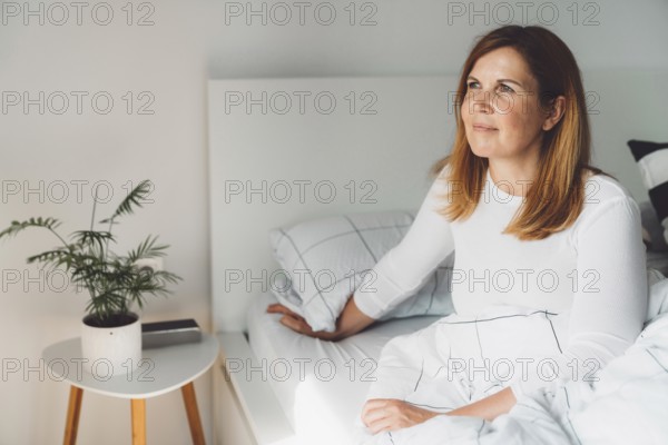 Cheerful happy caucasian woman relaxing at home on her day off work. Adult content woman spending time at home, in her apartment, resting on the couch, having a cup of coffee, feeling good