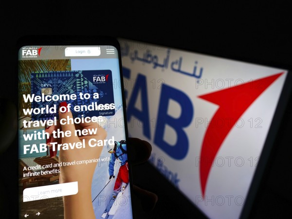 Stuttgart, Germany, 02-11-2022: Person holding cellphone with website of financial company First Abu Dhabi Bank (FAB) on screen with logo. Focus on center of phone display, Europe