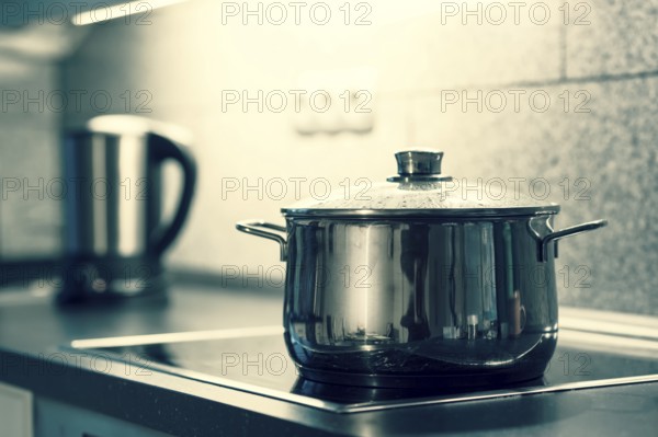 A saucepan with a glass lid is placed on an electric cooker