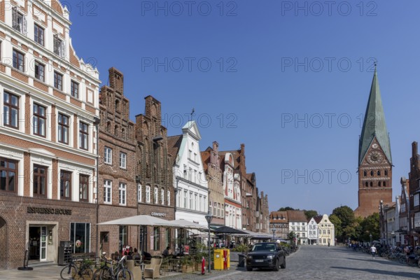 Historic surrounding gabled houses with many shops and restaurants on the square Am Sande in the medieval old town of Lüneburg and St. Johannis church with leaning tower, Hanseatic city of Lüneburg, Lower Saxony, Germany, Europe