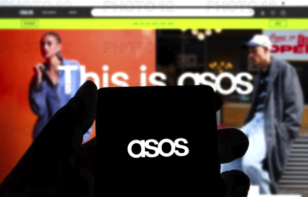 Dhaka, Bangladesh 14 Dec 2024:Cellphone with logo of British fashion retail company ASOS plc on screen in front of business website. Focus on center-left of phone display.