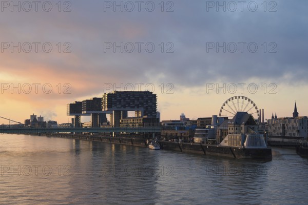 View over the Rhine with crane houses and Ferris wheel, sunrise, Cologne, Germany, Europe