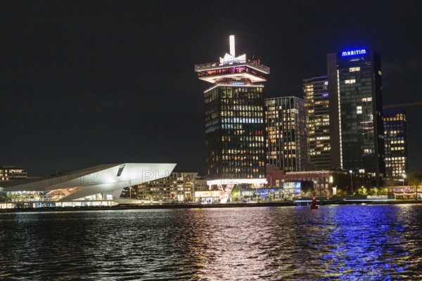 Illuminated skyline at night along a body of water with modern architecture and lights, Amsterdam, Netherlands