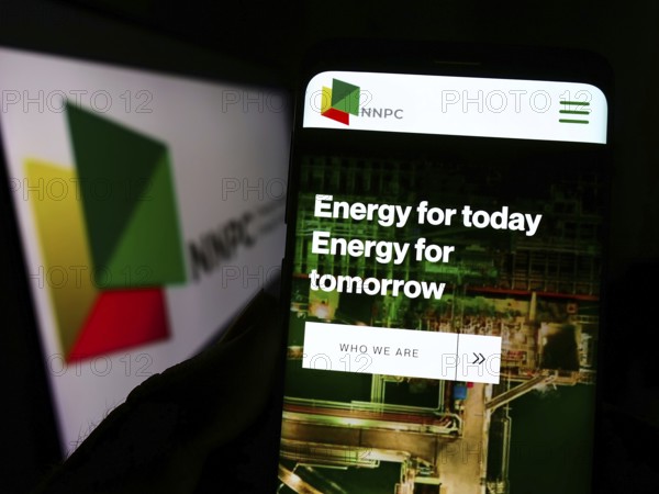 Stuttgart, Germany, 10-03-2022: Person holding cellphone with website of Nigerian National Petroleum Company Limited (NNPC) on screen with logo. Focus on center of phone display, Europe