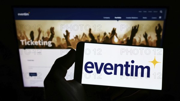 Stuttgart, Germany, 05-21-2022: Person holding smartphone with logo of German ticketing company CTS Eventim AG Co. KGaA on screen in front of website. Focus on phone display, Europe