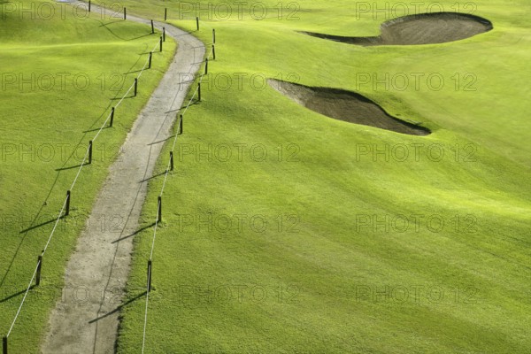 Golf course green grass hill field with holes and track way