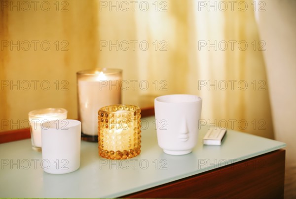 Table with many burning lighting scented candles and aromatic incense sticks in spa massage salon or yoga studio, selective focus. Meditation place in home interior. Aromatherapy concept