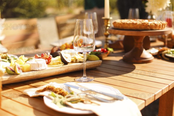 Empty wineglass placed near board with fruits on banquet table on sunny summer day