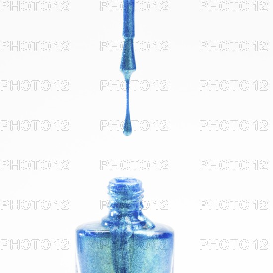 Glitter blue nail polish falling into bottle white background