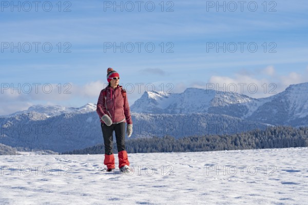 Pretty active senior woman snowshoeing in the Allgäu Alps near Oberstaufen with a view of the Bregenzerwald, Vorarlberg, Austria, Europe