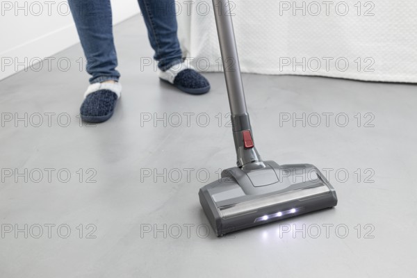 Woman cleaning with a cordless vacuum cleaner in a modern bedroom. Copy space