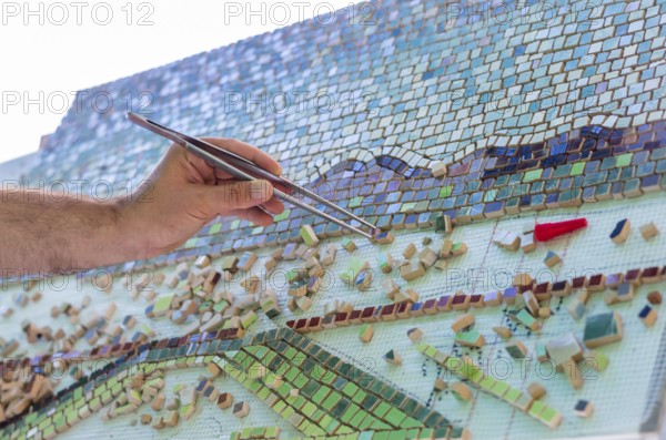 Mosaic as a ceramic or ceramic mosaic. The man organizes design with a tweezers a puzzle of ceramic elements for the construction of ceramic works. Artistic mosaics of terracotta. Bulgaria
