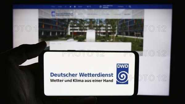 Stuttgart, Germany, 06-06-2024: Person holding cellphone with logo of German meteorological service Deutscher Wetterdienst (DWD) in front of webpage. Focus on phone display, Europe