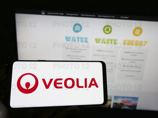 Stuttgart, Germany, 01-15-2023: Person holding cellphone with logo of French company Veolia Environnement SA on screen in front of business webpage. Focus on phone display, Europe