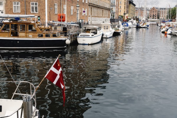 Copenhagen, Denmark, August 12, 2016: Port of Copenhagen with boats and ships moored. Danish flag on foreground, Europe