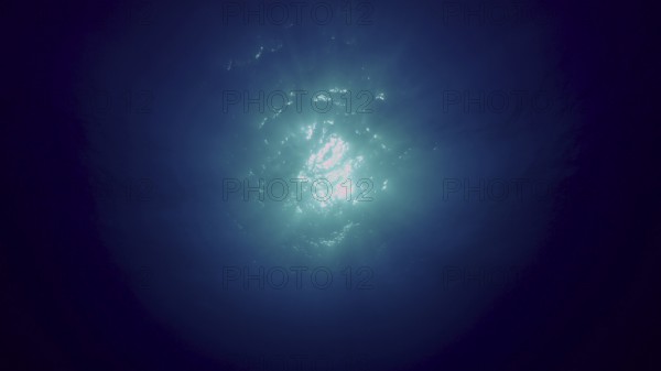 View of sun light from blue abyss, slow motion. Light filters down through blue water. Underwater sun rays in depth ocean. Underwater light, sun light shine under deep water with ripples on surface