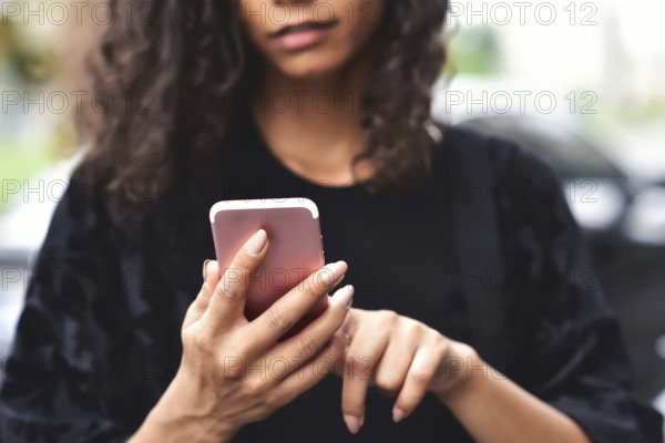 Close up portrait of beautiful young african american woman reading text message on mobile phone at street
